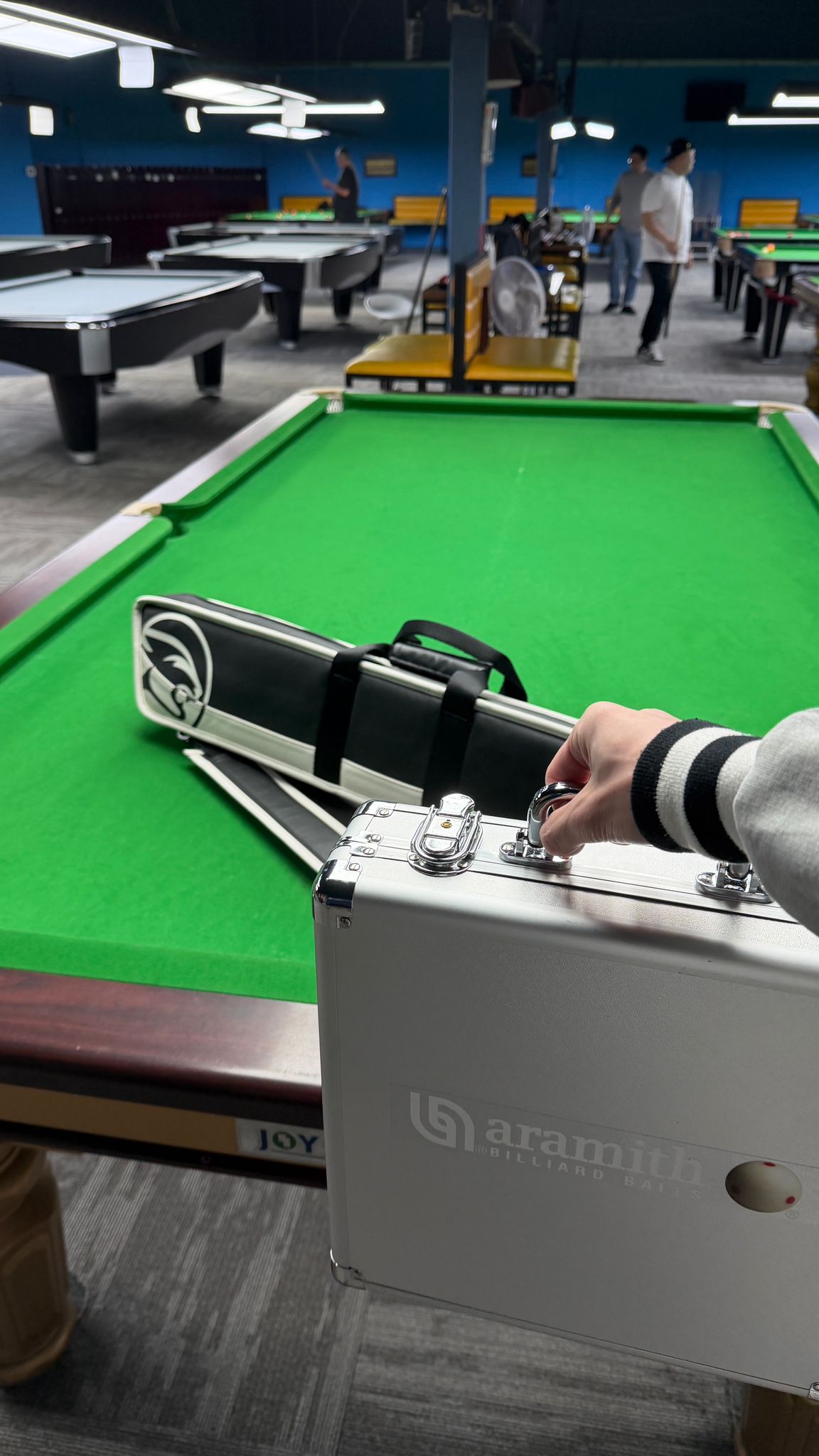 A second view of the same pool room, the professional table standing under low ceiling lights.