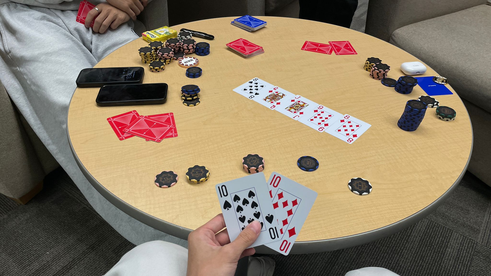 A late, quiet poker hand with friends, cards held low.
